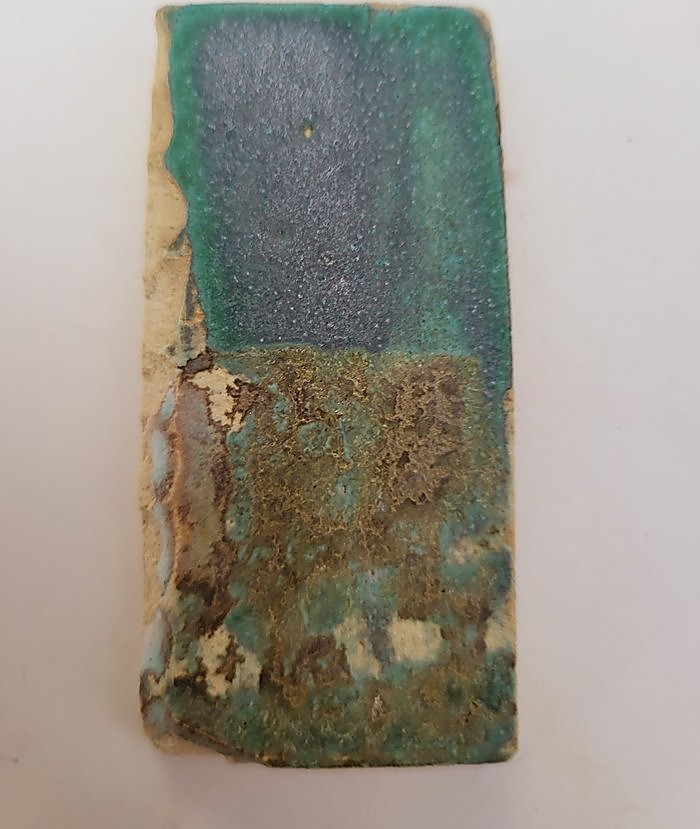 A test tile in Weathered Green, the top half left as the green alone and the bottom half gone olive and mottled where Gen’s Satin Matte has been applied over it