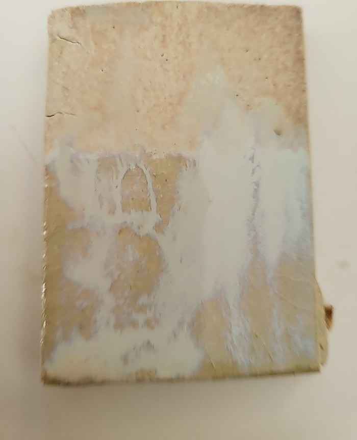 A test tile in Gen’s Satin Matte, the lower half turned glassy and pearl-white where clear glaze has been laid over it