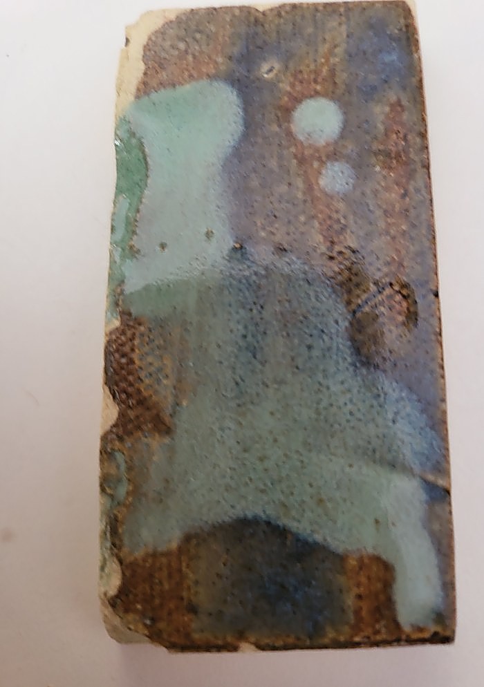A test tile in Floating Blue — mottled blue, rust and brown, with pale Chun Seafoam dots sitting as soft rounds across it