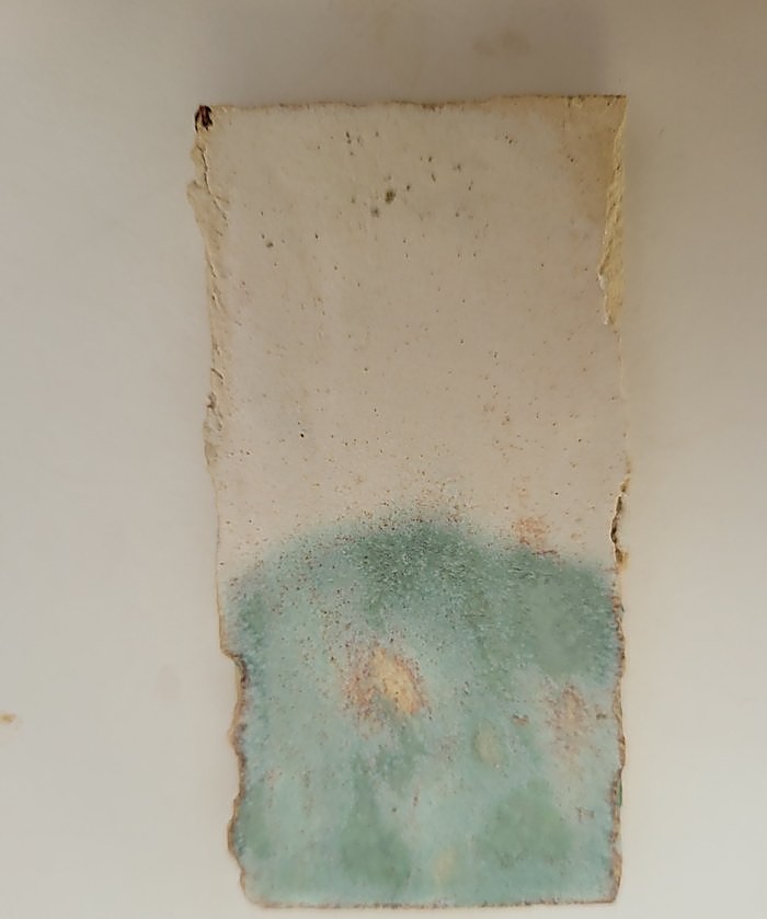 A test tile in Gen’s Satin Matte, the lower half a soft seafoam green where Chun Seafoam has been applied over it