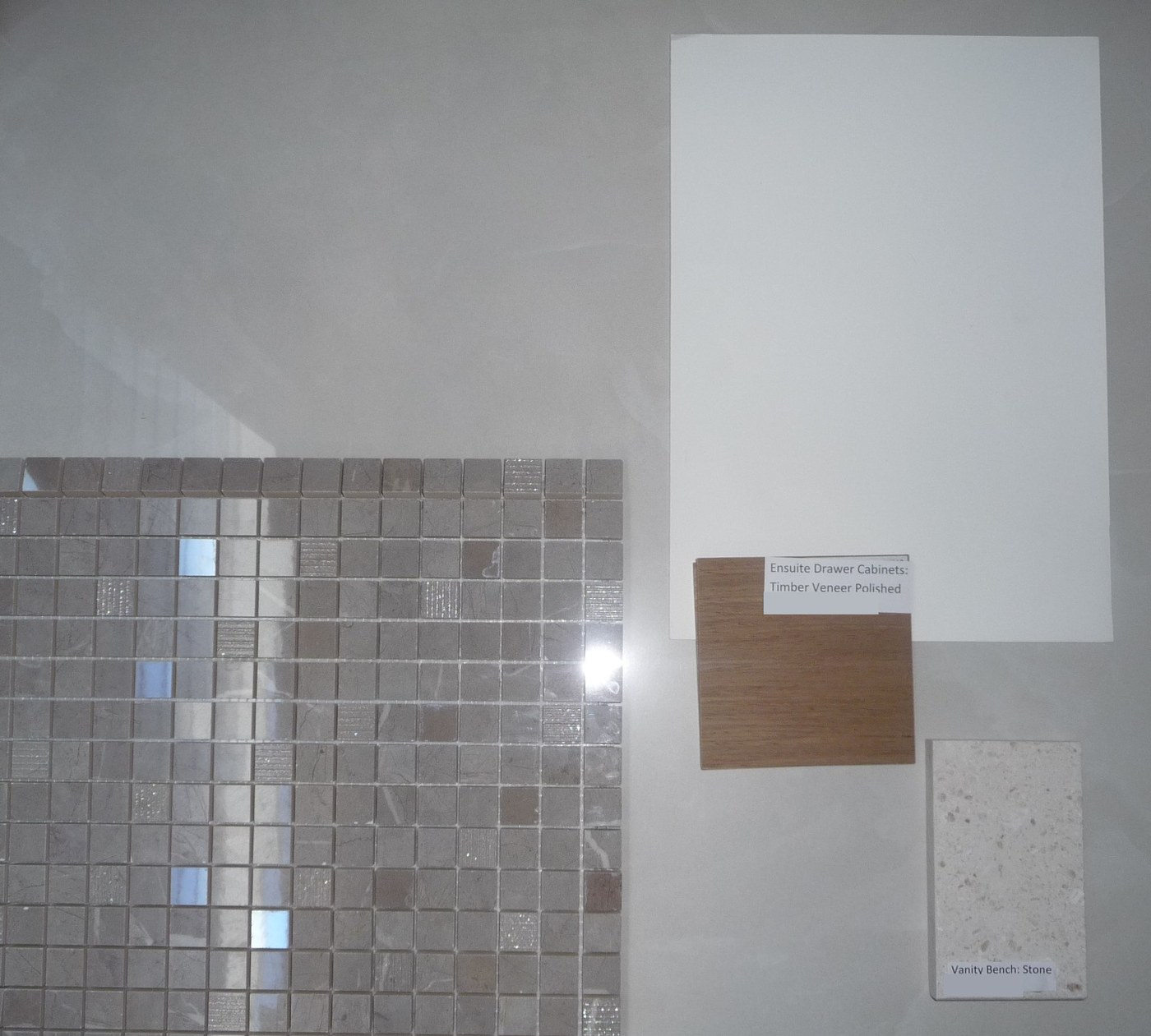 The ensuite finishes board &mdash; a sheet of the feature mosaic laid out beside a polished timber veneer sample labelled for the drawer cabinets and a stone sample labelled for the vanity bench