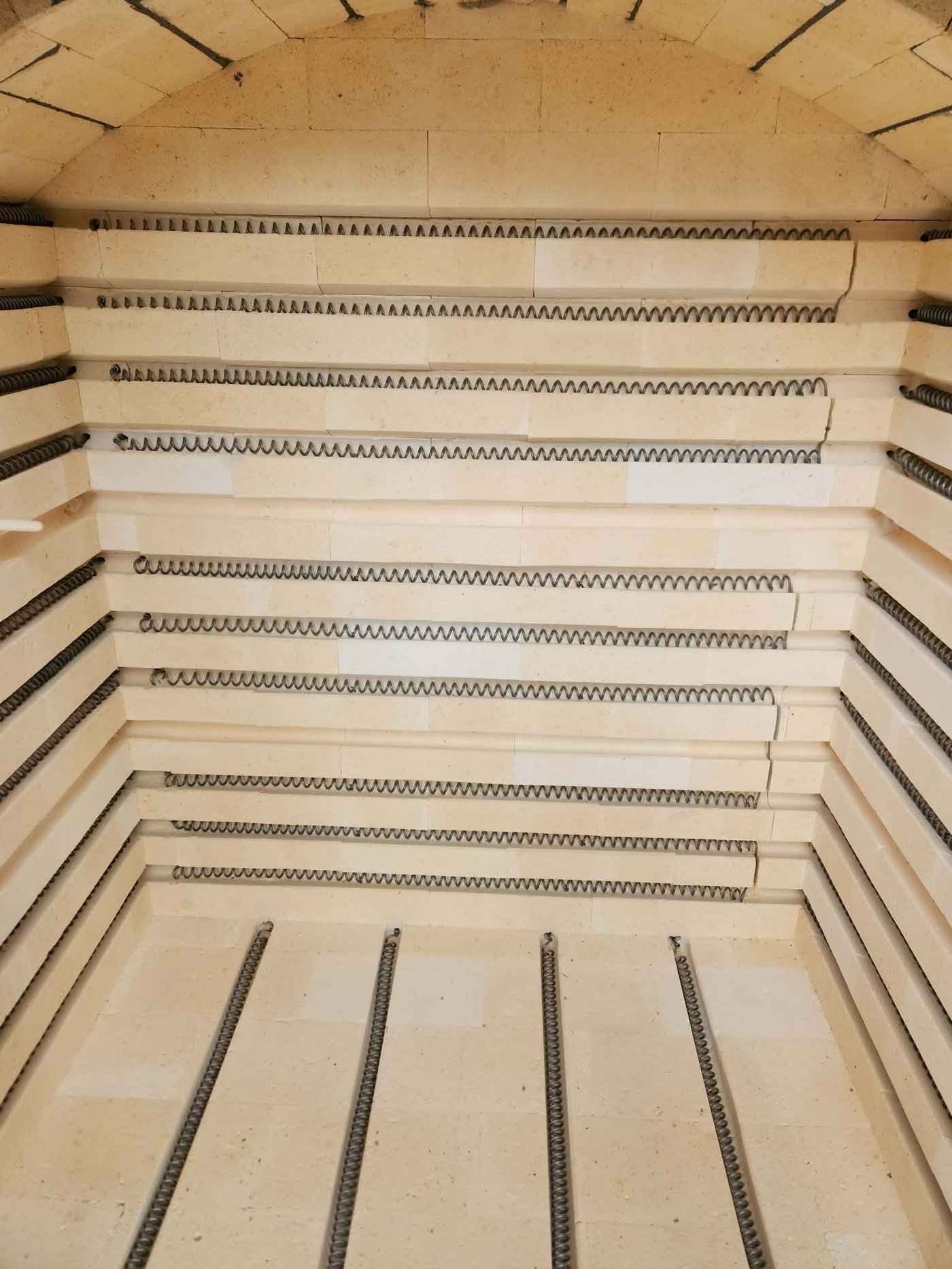 The empty interior of the new kiln, looking up at the arched brick ceiling with rows of coiled heating elements set into the walls