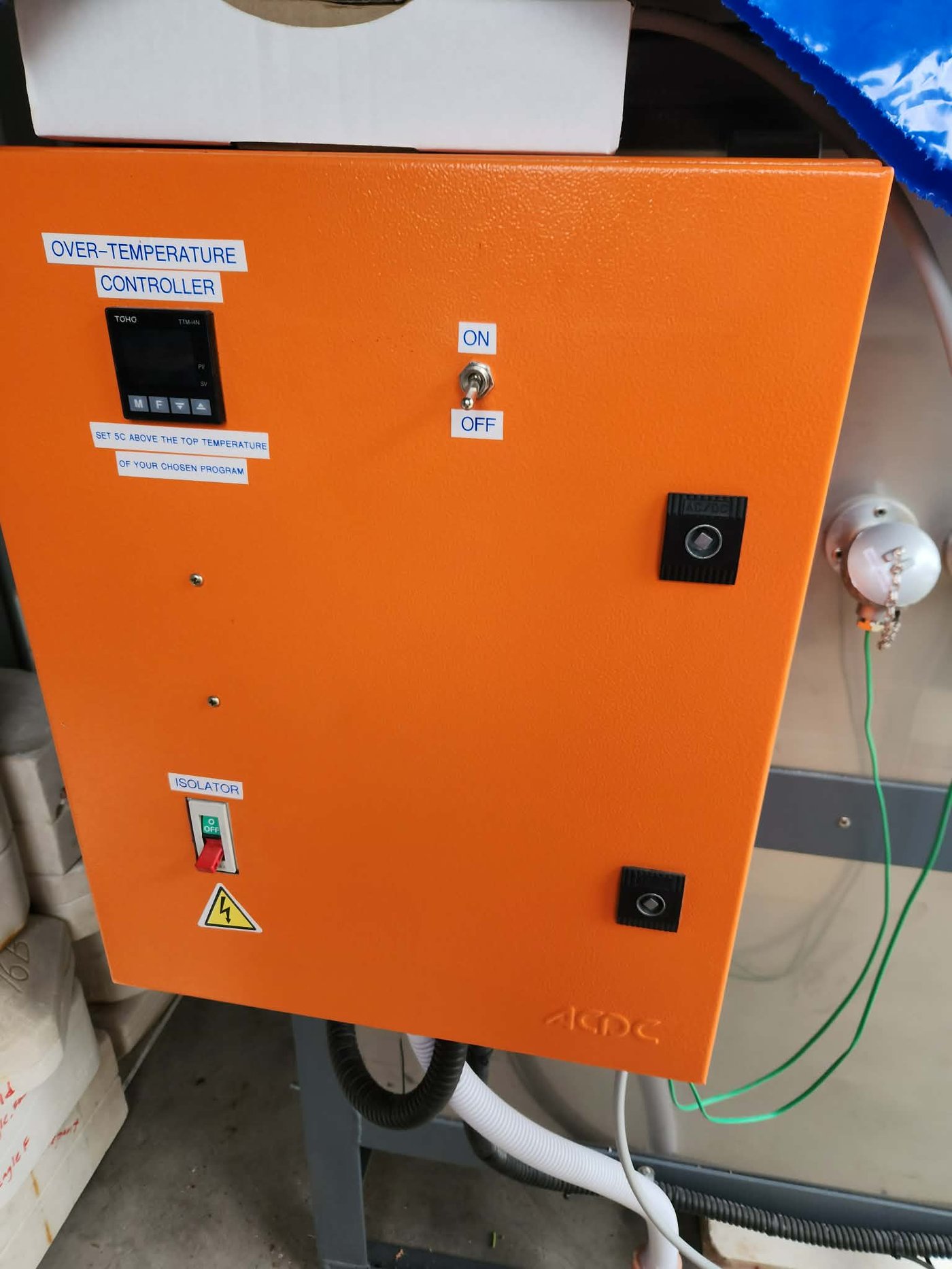 The kiln's orange control cabinet, showing the over-temperature controller, the on/off toggle and the isolator switch