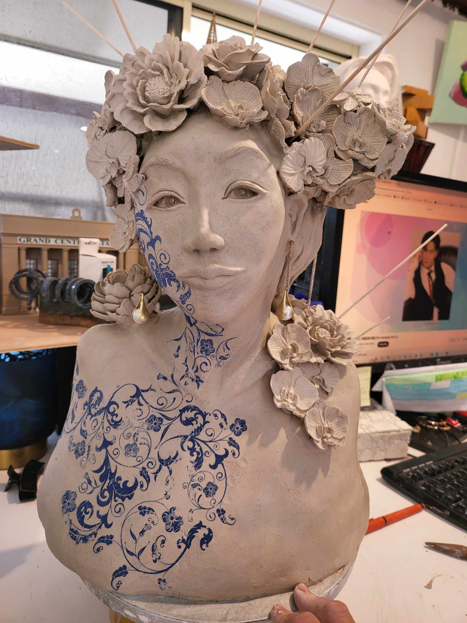 The Florist in greenware &mdash; a bust crowned with hand-modelled orchids and roses, pearl drop earrings, a scrolling blue-and-white floral pattern across the cheek, neck and chest