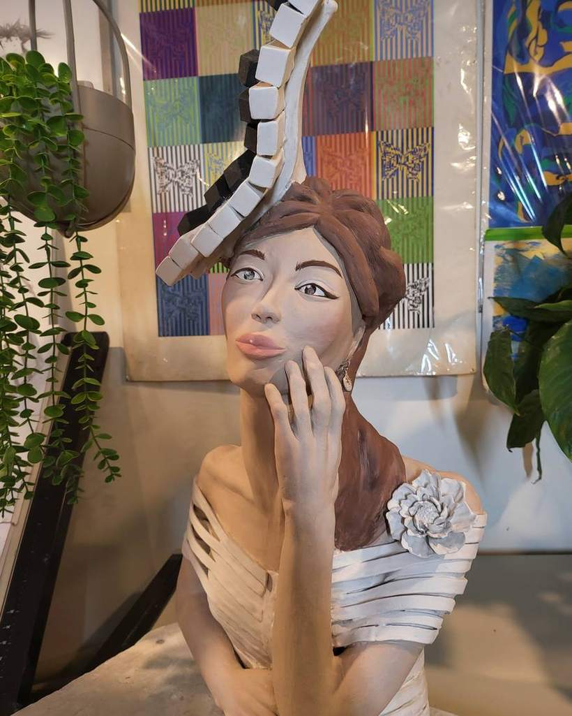 The Pianist &mdash; a run of black and white piano keys curving up from her head, one hand raised to her face, the hair and features painted and a white flower at the shoulder