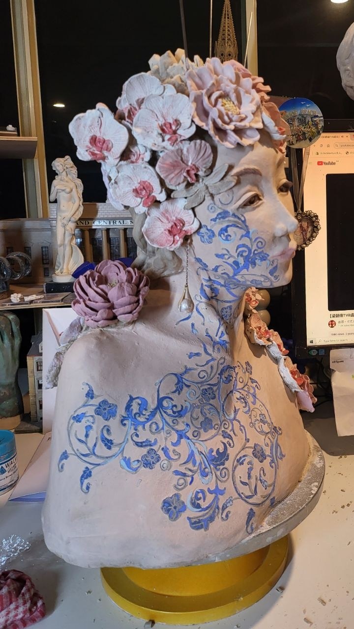 The Florist from the side &mdash; the blue scrolling pattern running from the cheek down the throat and across the chest and shoulder, the orchids in the hair now touched with pink, a mauve rose at the back of the shoulder and smaller roses trailing over the front