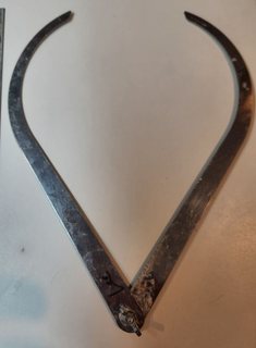 A pair of curved stainless steel sculpture calipers, open