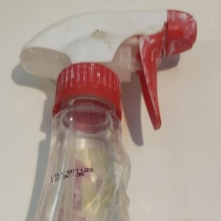 A hand-trigger spray bottle, clay-spattered from studio use